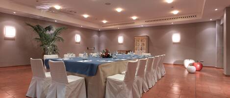 A conference room with a long table, white chairs, and a blue tablecloth.