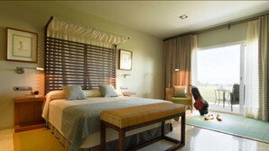A hotel room with a large bed, a bench, a chair, and a view of the outdoors.