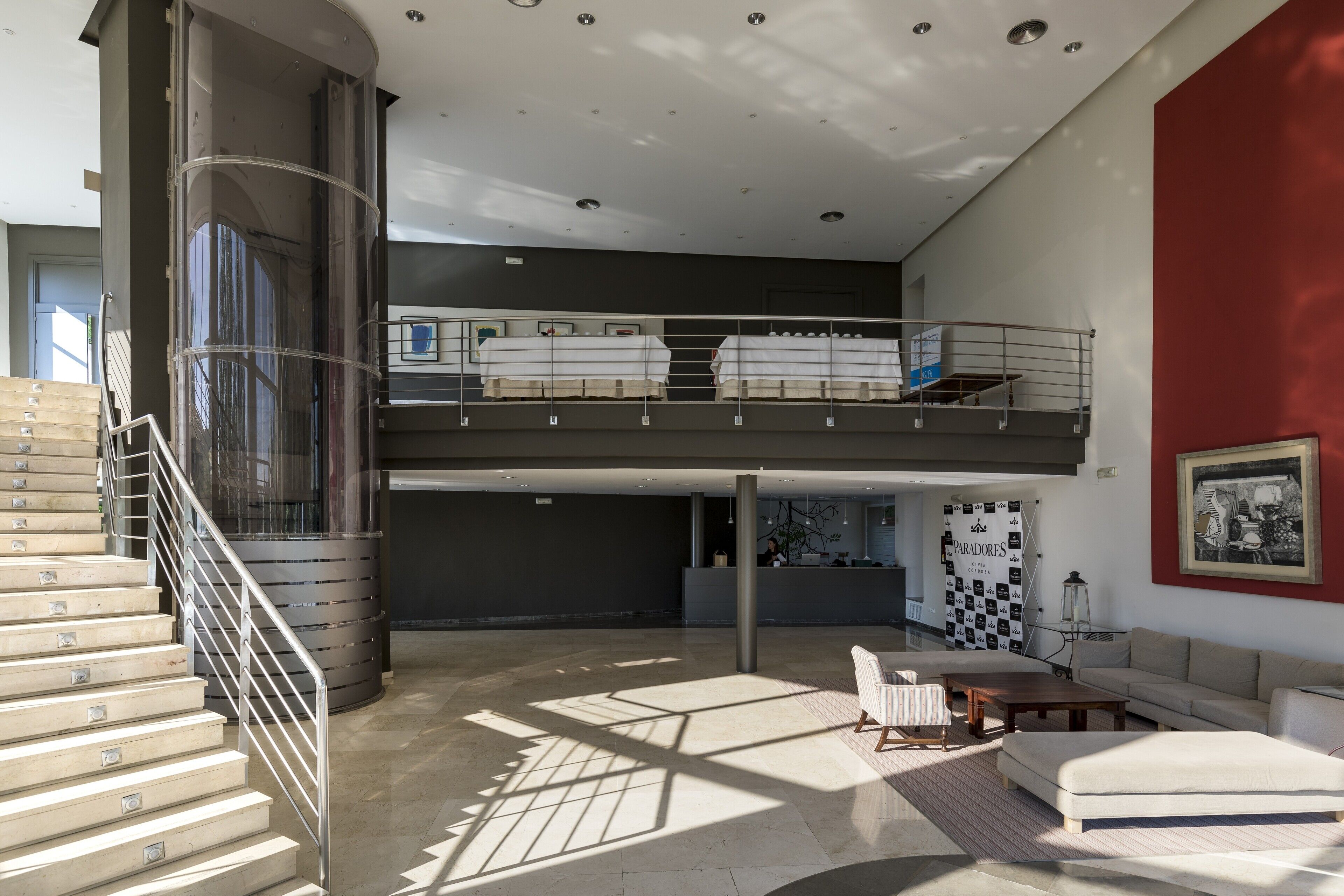 Un interior espacioso con una escalera, un entrepiso con camas, un sofá y un cuadro en la pared.