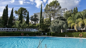 Una piscina de aguas cristalinas, rodeada de abundante vegetación y árboles altos.