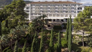 Un hotel de varios pisos con balcones, rodeado de exuberante follaje y palmeras.
