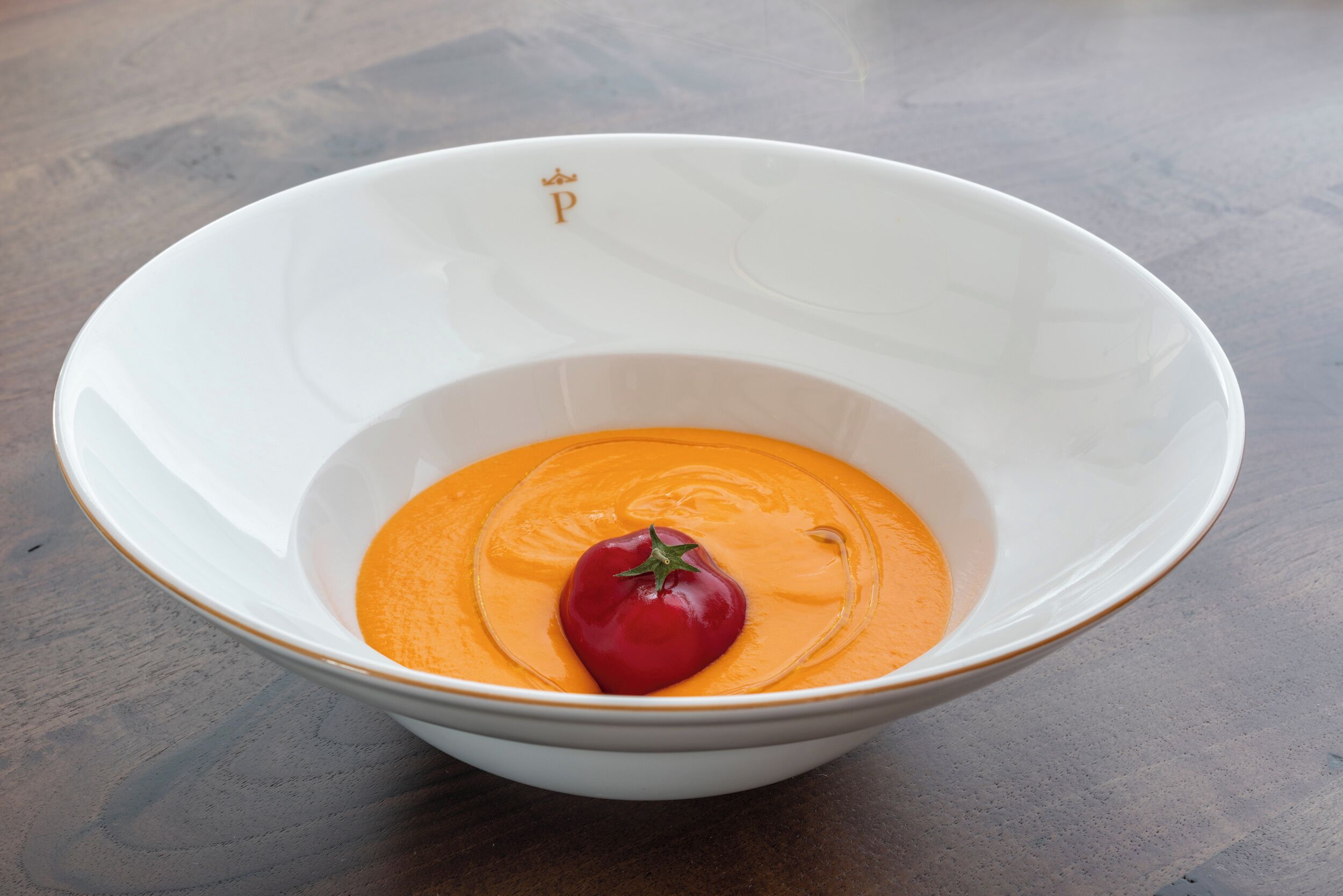 Eine weiße Schüssel mit einer roten Tomate auf einer strukturierten Oberfläche.