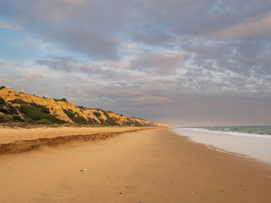 A beach with a sandy shore and a rocky cliff in the background.