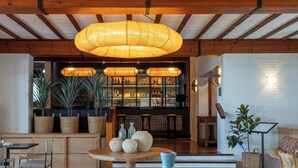 Un interior espacioso con techos altos, vigas de madera y una zona de estar central con una mesa y sillas.