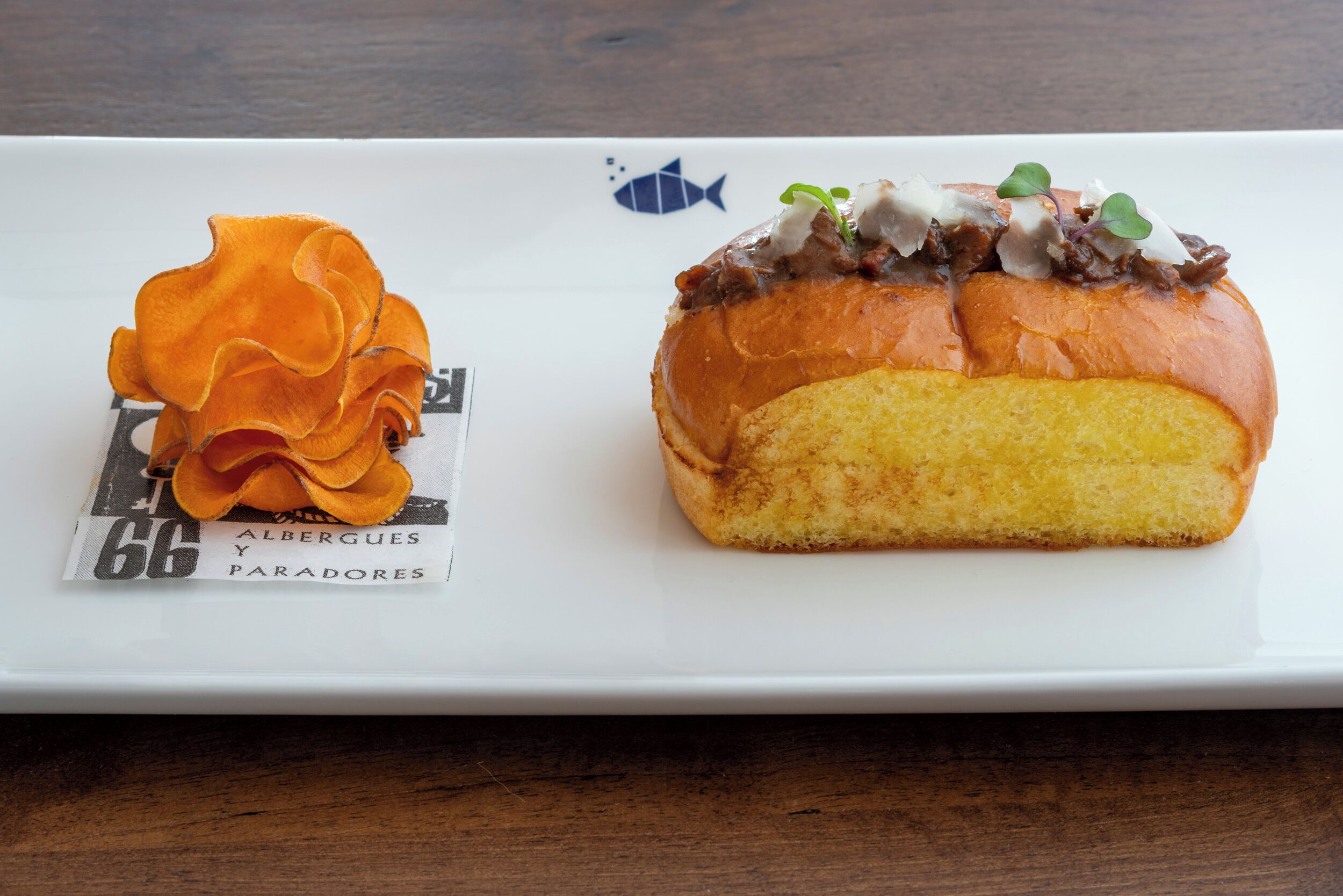 Un plato blanco rectangular con un sándwich y un adorno.