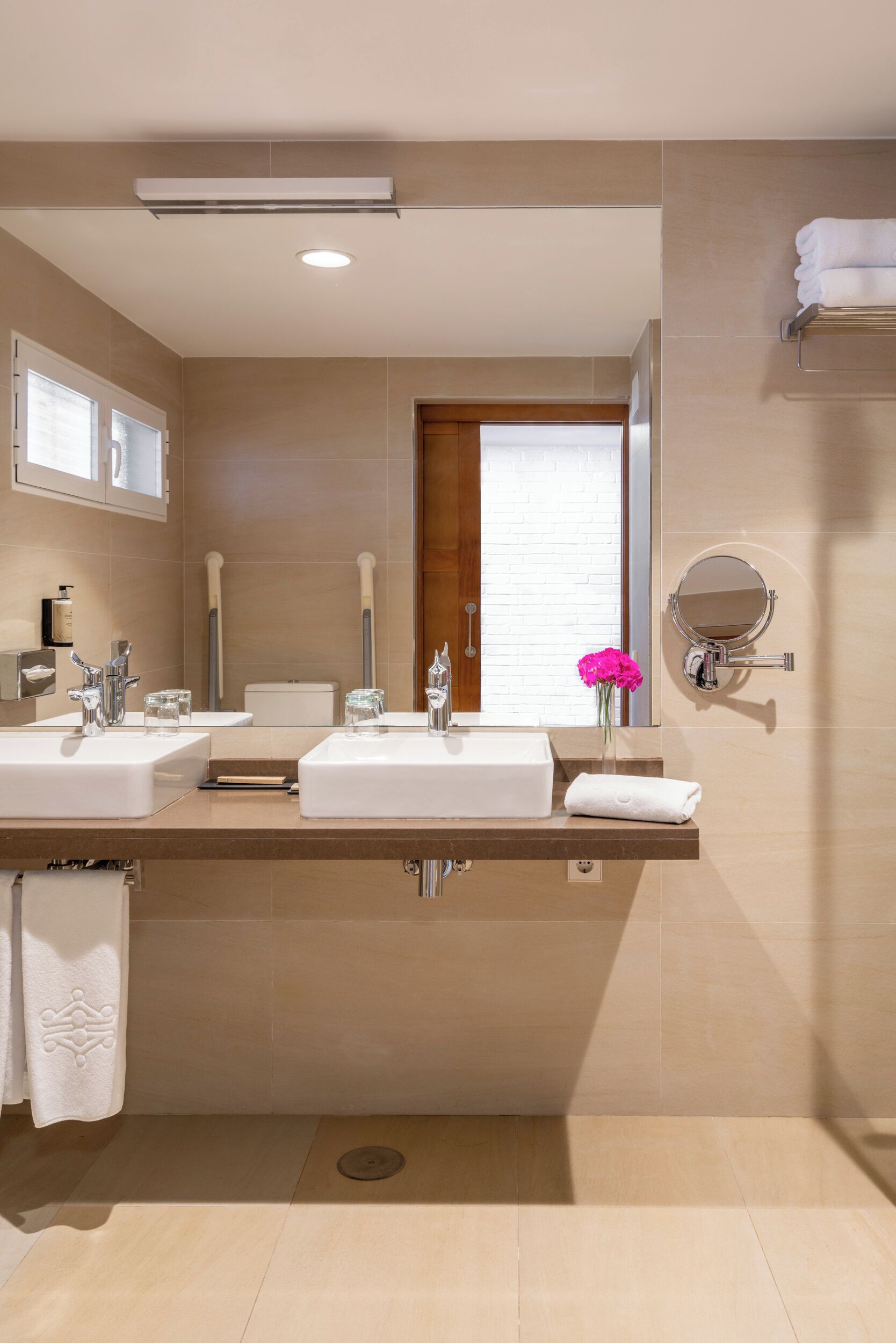 A modern bathroom with two sinks, a mirror, and a window.