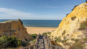 Una escalera de madera que lleva a una playa con cielos despejados.