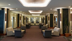A spacious lobby with multiple seating areas, a central table, and a high ceiling with recessed lighting. - Palan Hotel (Erzurum)