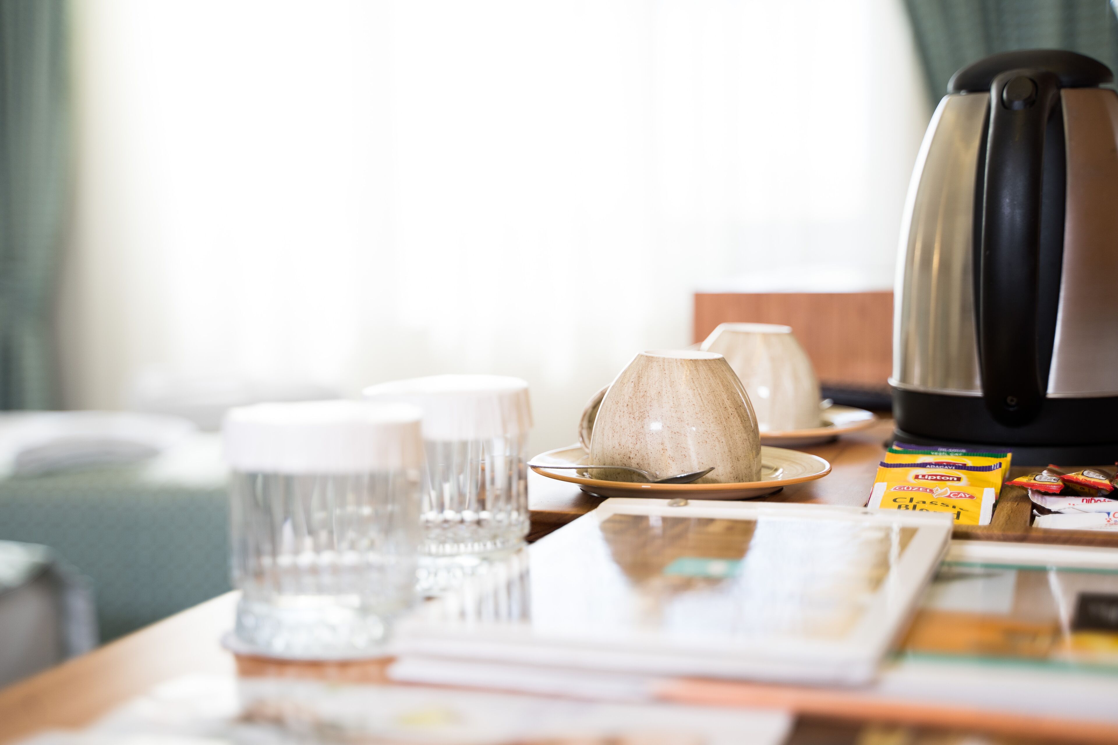 Een tafel met een waterkoker, een kopje, een bord en een doos Lipton thee.