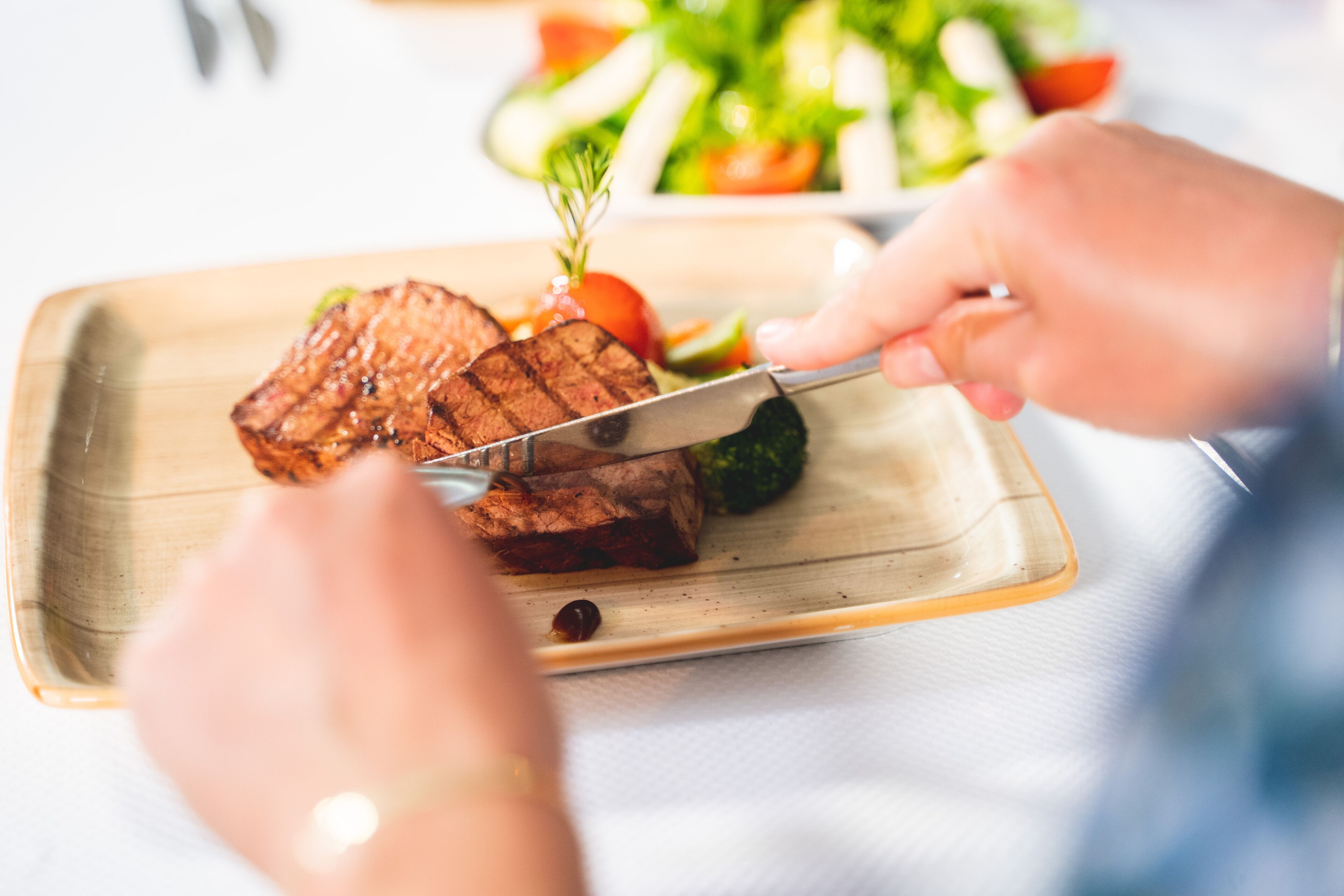 Iemand snijdt een steak op een houten snijplank.