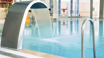 Una piscina con fuente, zona de estar interior y un restaurante de comida rápida al fondo.