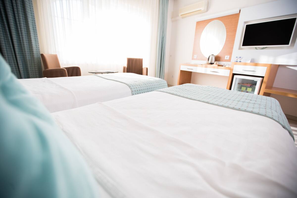 Una habitación de hotel con dos camas, un escritorio, una silla, un televisor y un minibar.
