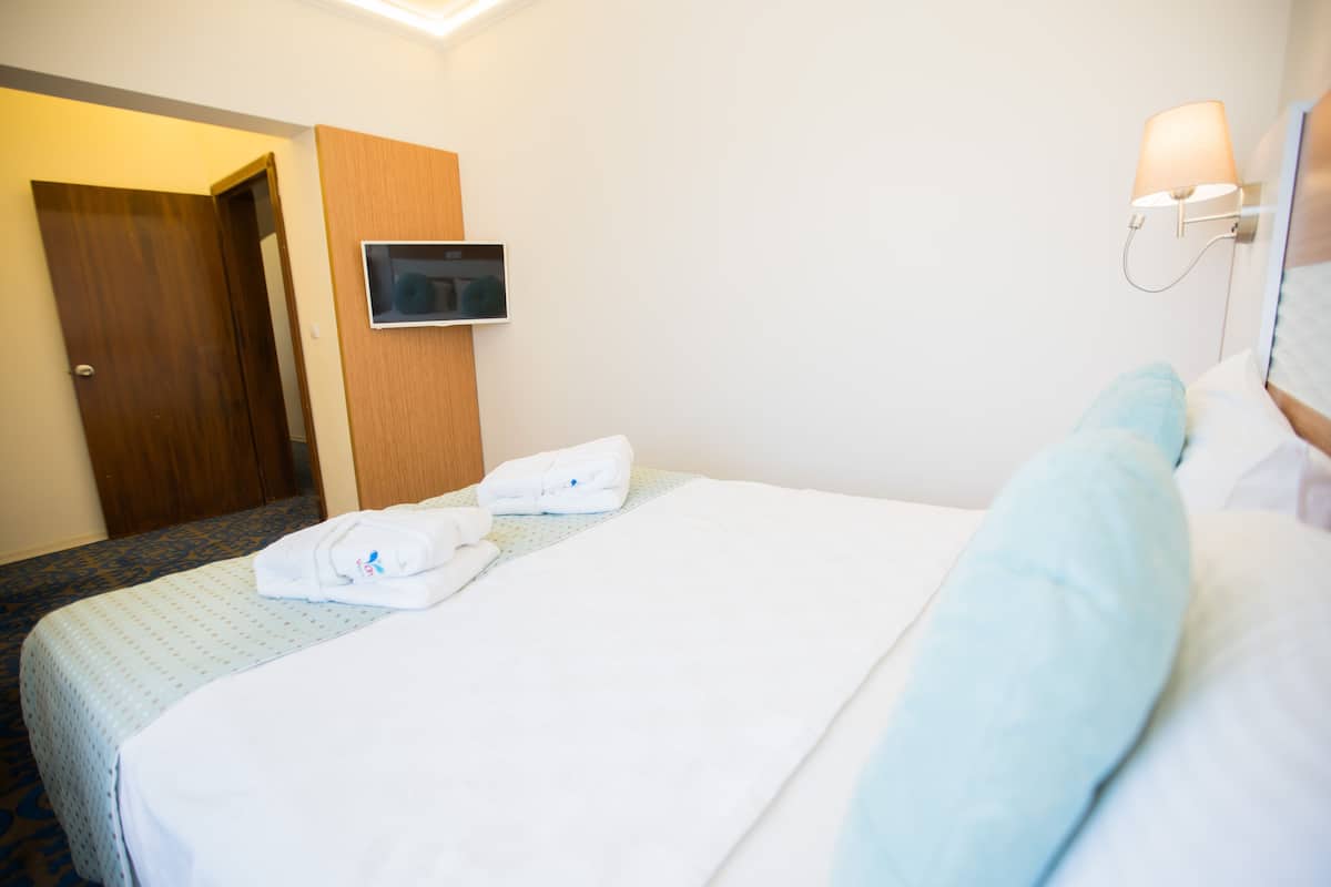 Una habitación de hotel con cama, televisor en la pared y una puerta.