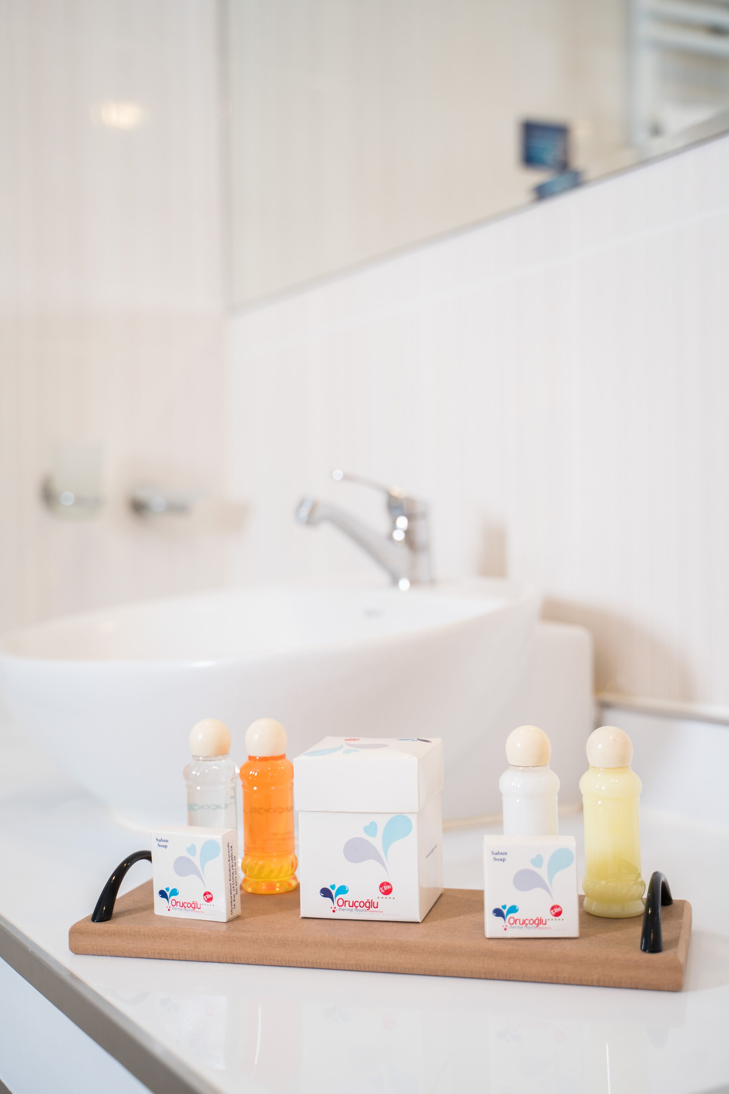 A bathroom with a sink and toiletries on a wooden tray.