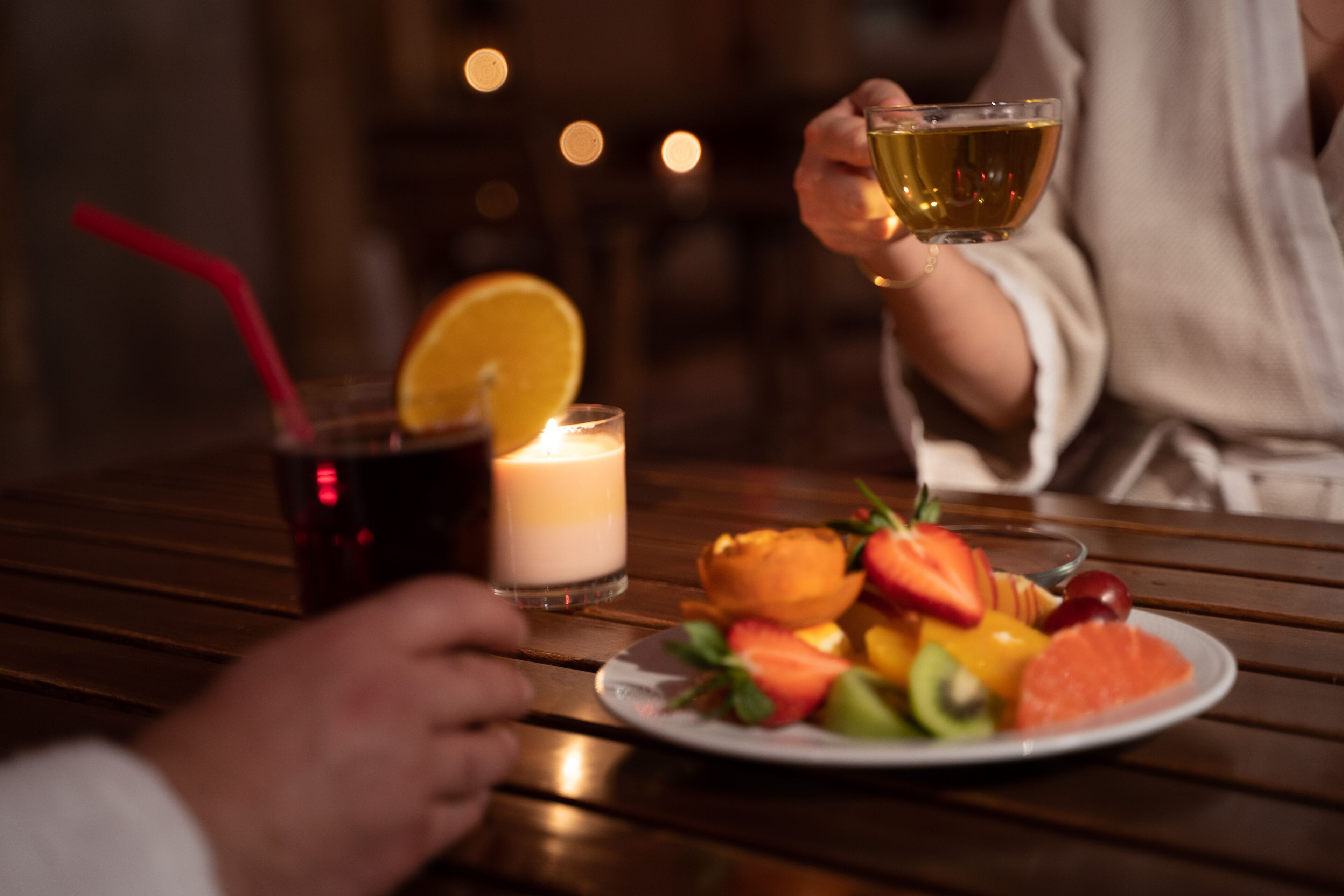 A wooden table with a plate of fruit and a glass of drink.