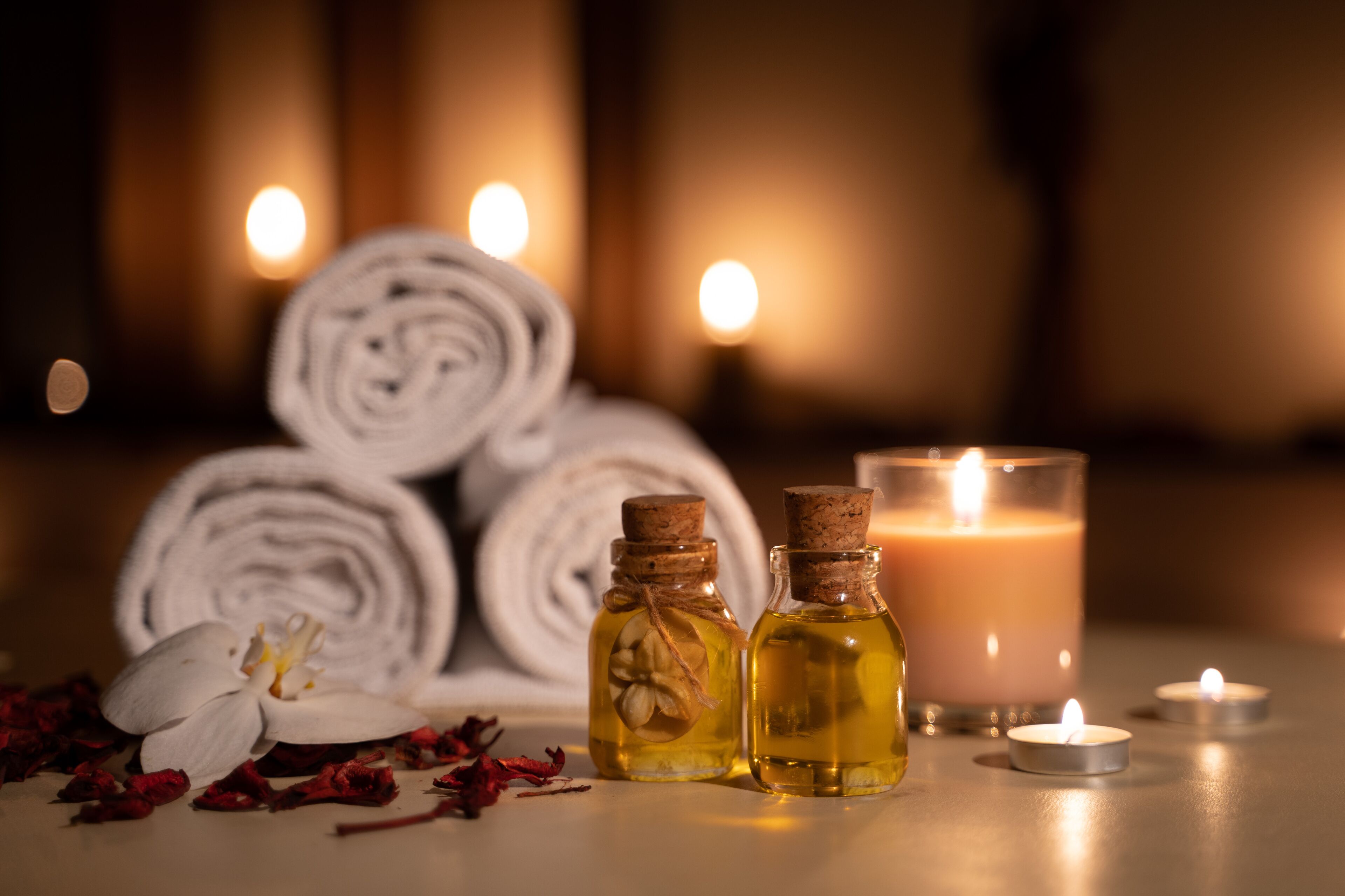 Un ambiente de spa con toallas enrolladas, velas y botellas de aceites esenciales.