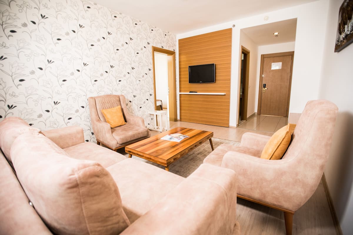 Una sala moderna con una mesa de centro de madera, dos sofás, un televisor montado en un panel de madera y un papel tapiz estampado.