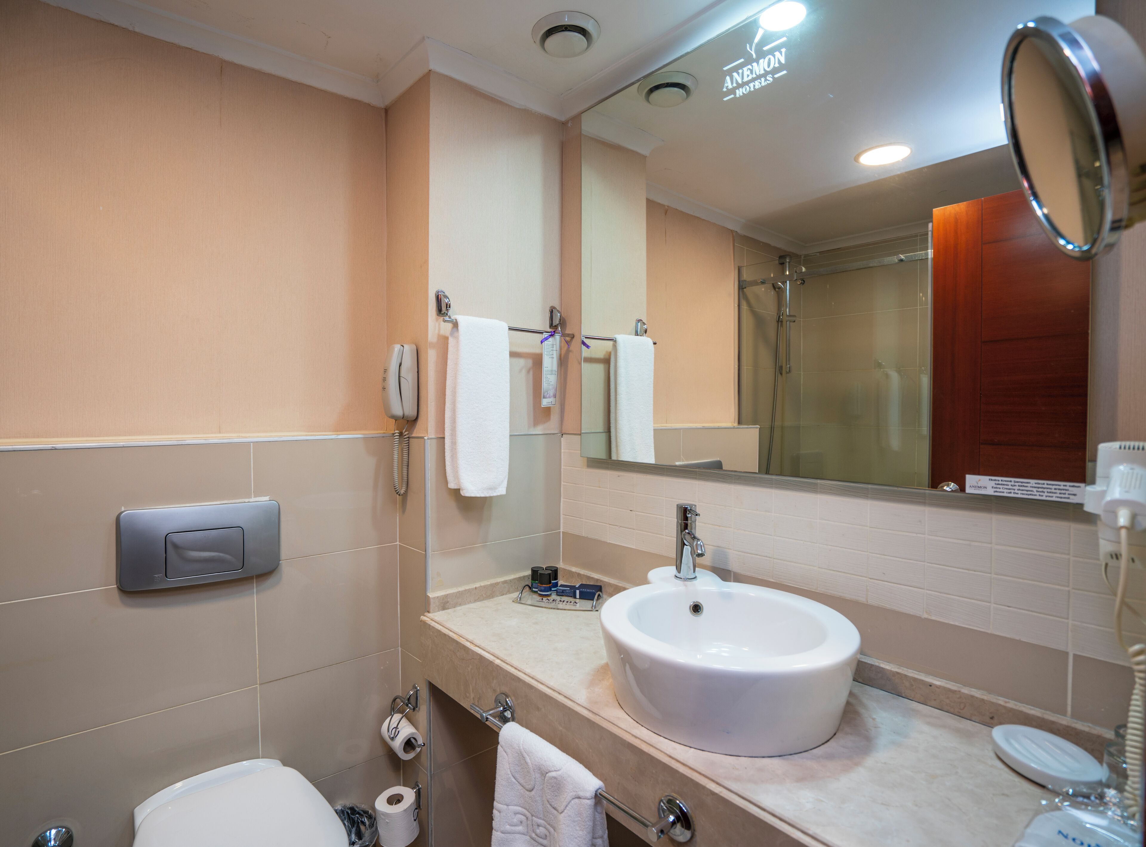 A hotel bathroom with a sink, toilet, and a mirror.