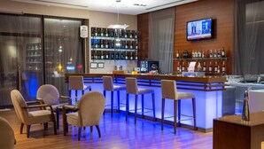 A bar area with wooden flooring, bar stools, and a TV mounted on the wall.