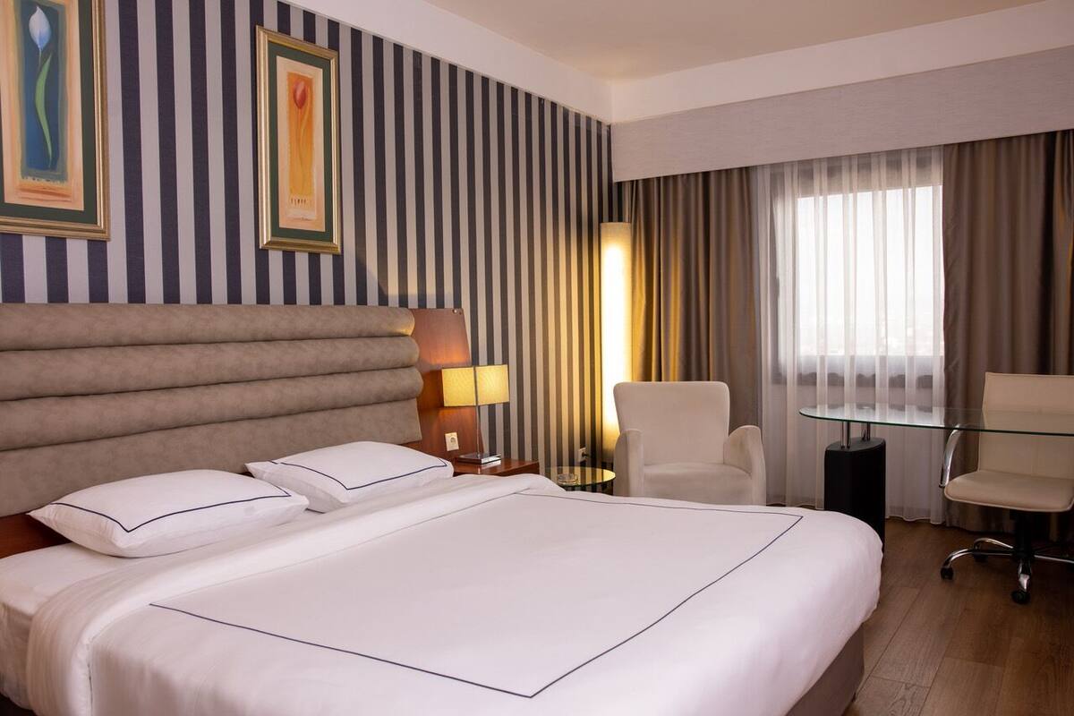 Une chambre d’hôtel avec un grand lit, deux tables de chevet, un bureau et une chaise.