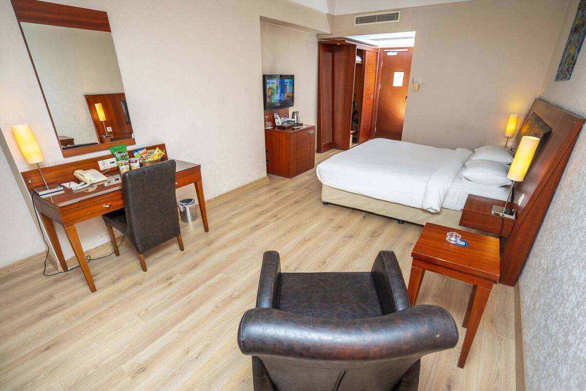 Une chambre d’hôtel équipée d’un lit, d’un bureau, d’une chaise, d’une télévision et d’un miroir.