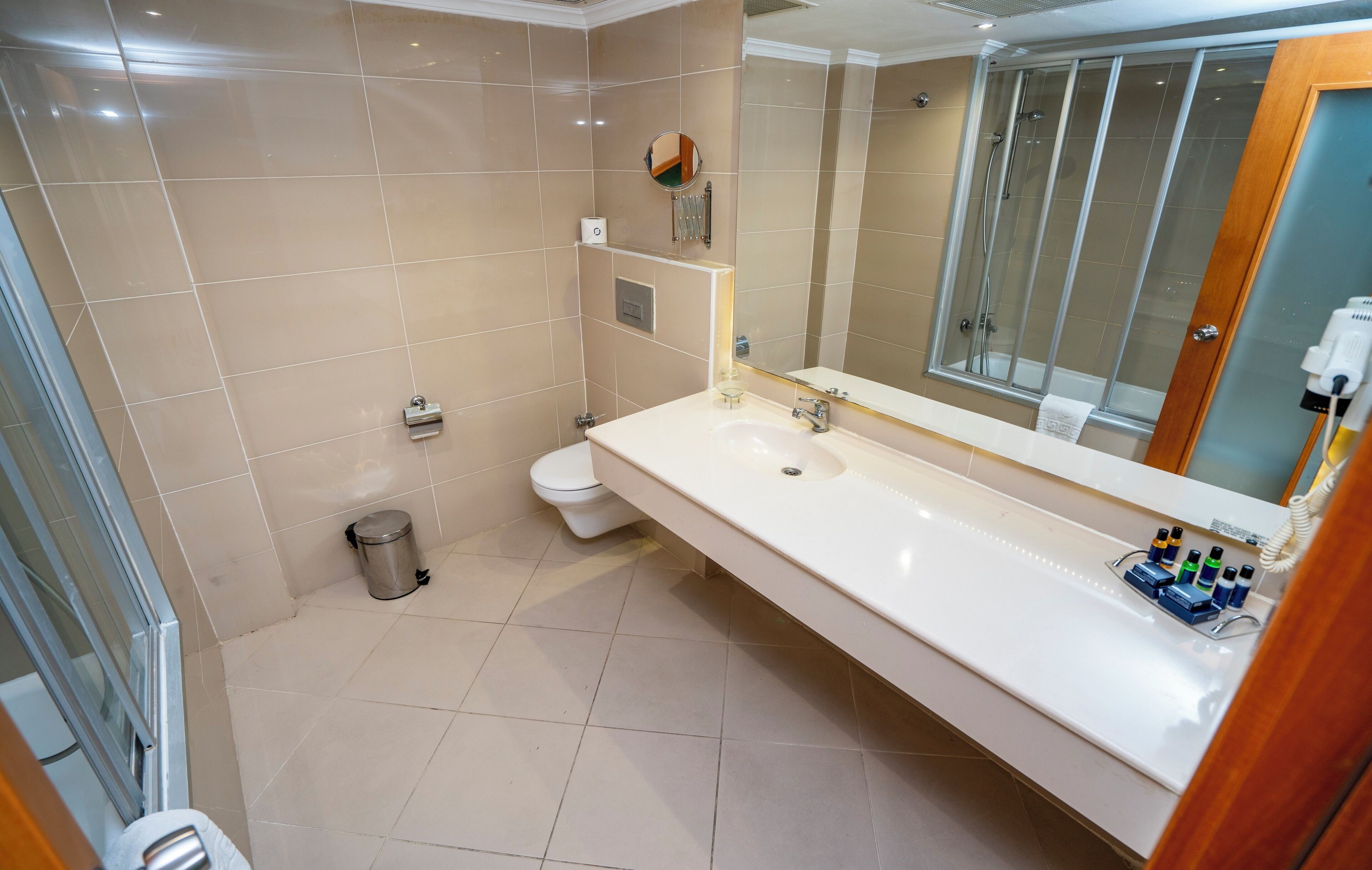 Un baño moderno con un espejo grande, un lavabo y un inodoro.