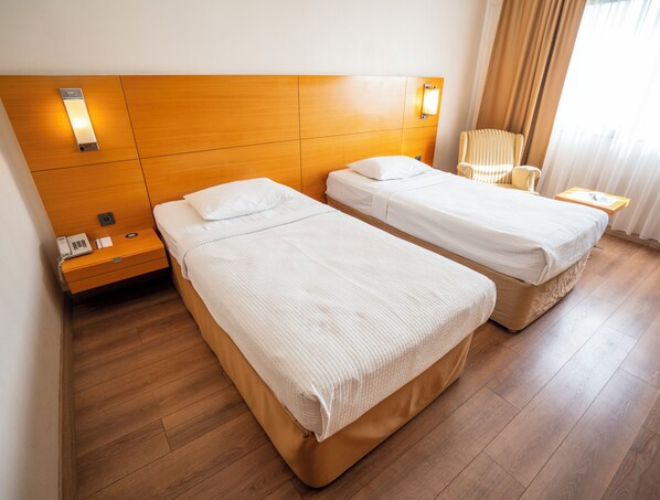 A hotel room with two single beds, wooden headboard, bedside lamps, a telephone, and a small table with a tray. -  Anemon Kent Ege Otel  (Izmir)