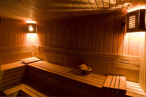 A sauna with wooden benches and a small bucket.