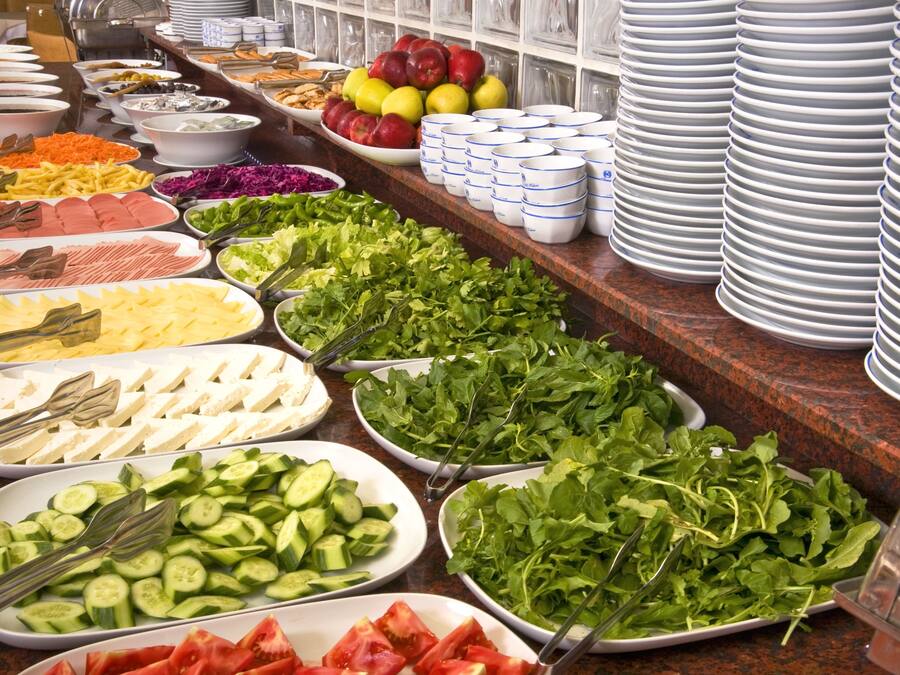 Un bufé con diversas opciones de comida, incluyendo frutas, verduras y quesos.