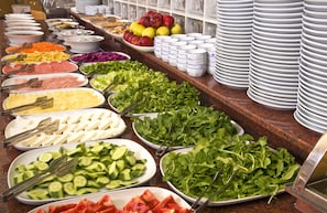 A buffet with various food items including fruits, vegetables, and cheeses.
