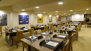 A conference room with multiple tables, chairs, water bottles, nameplates, and artwork on the walls. - Hotel Buyuk Keban (Istanbul)