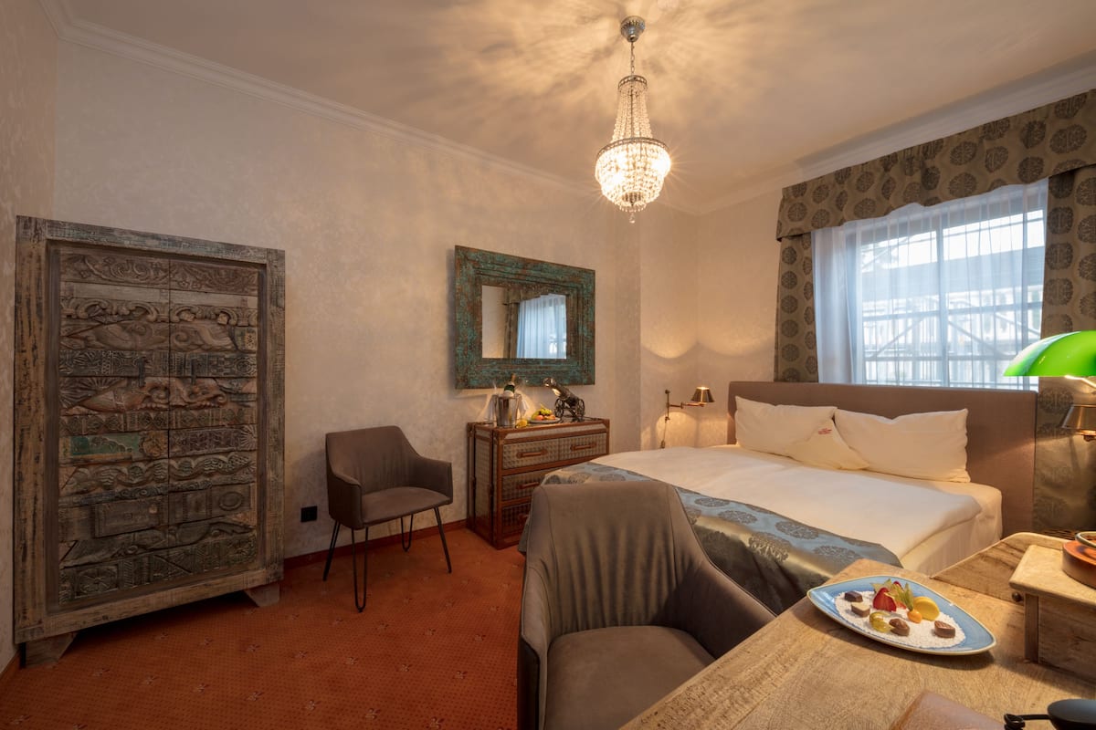 Ein Hotelzimmer mit einem Bett, einem Schreibtisch, einem Sessel, einem Schminktisch und einer Deckenleuchte.
