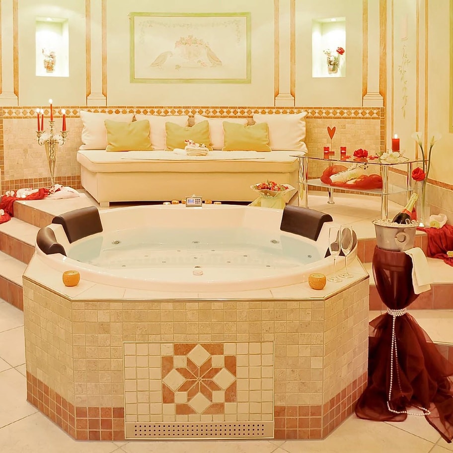 A luxurious bathroom with a large freestanding bathtub, a vanity with a mirror, and a decorative wall with framed artwork.