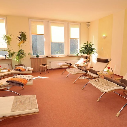 A room with multiple reclining chairs, a small table, and potted plants.