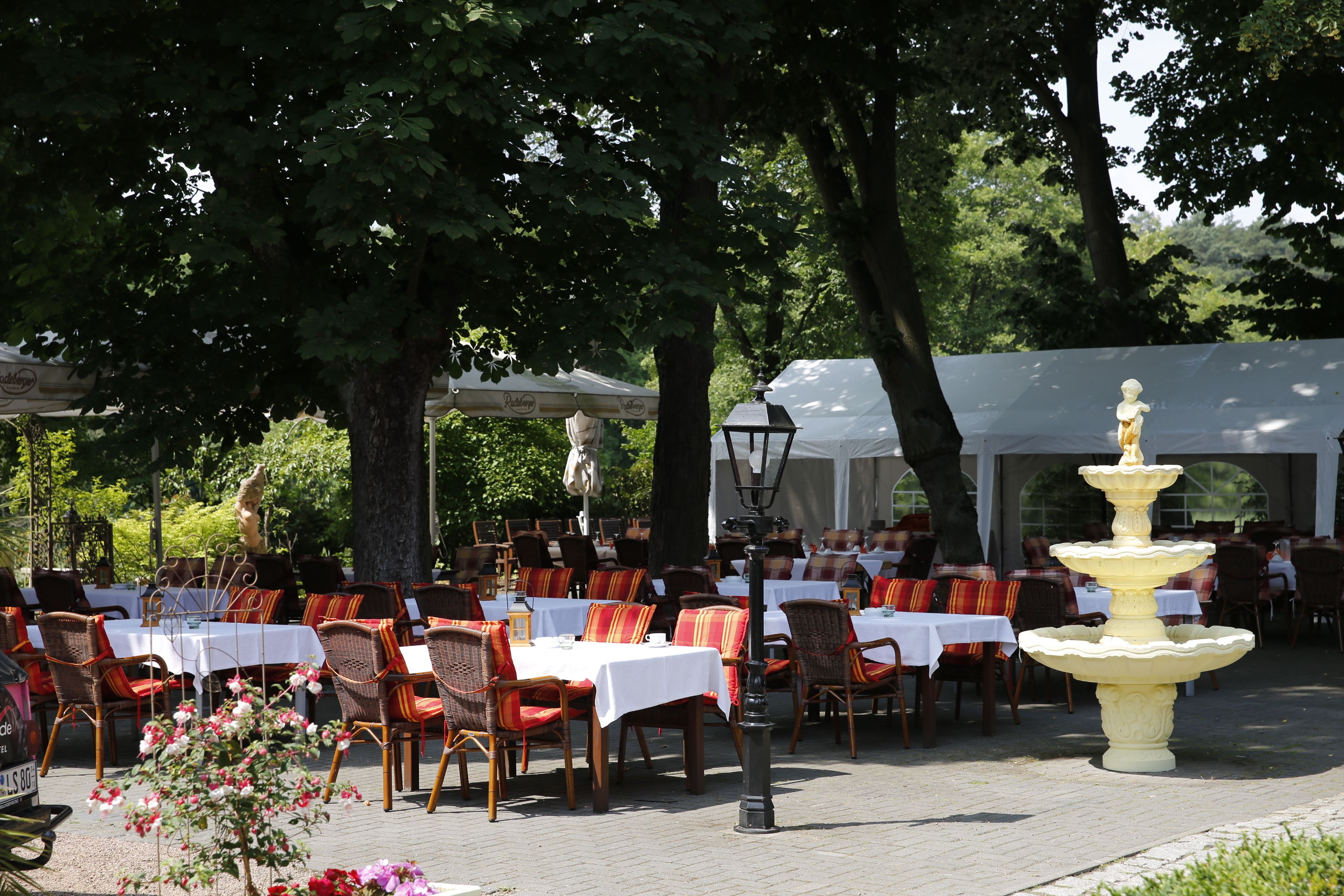 Ein Außenbereich mit Tischen und Stühlen, einem Zierbrunnen und einer Statue.