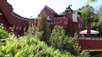 Ein schlösserähnliches Gebäude mit roter Fassade, weißer Verzierung und einem Turm mit einer Flagge.
