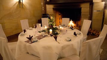 A round dining table set for four with white tablecloths, candles, and floral centerpieces.