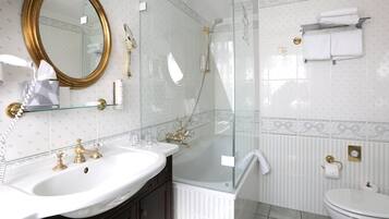 A bathroom with a large mirror, two sinks, a shower, and a toilet.