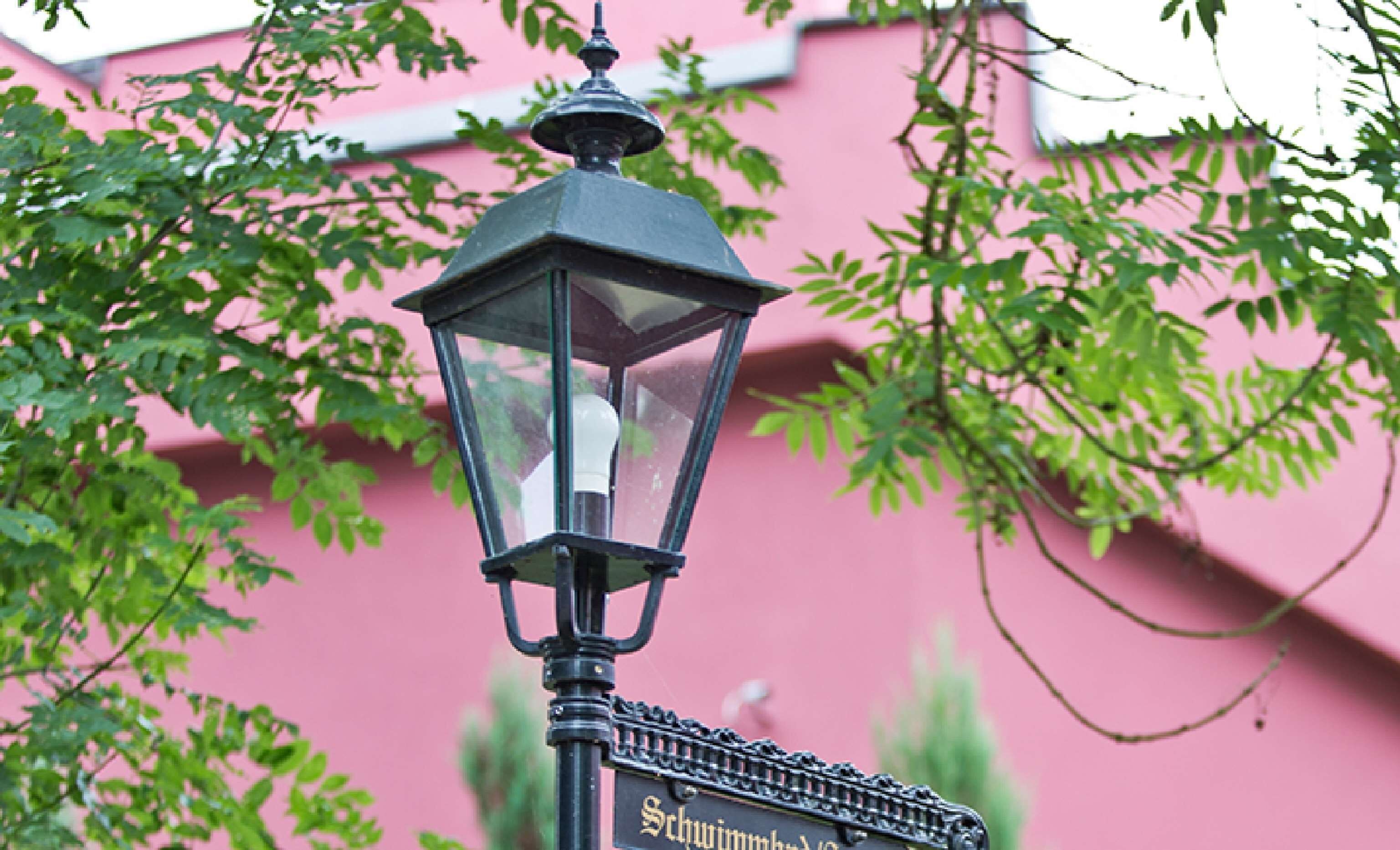 Una farola con una carcasa de cristal transparente y una parte superior decorativa.