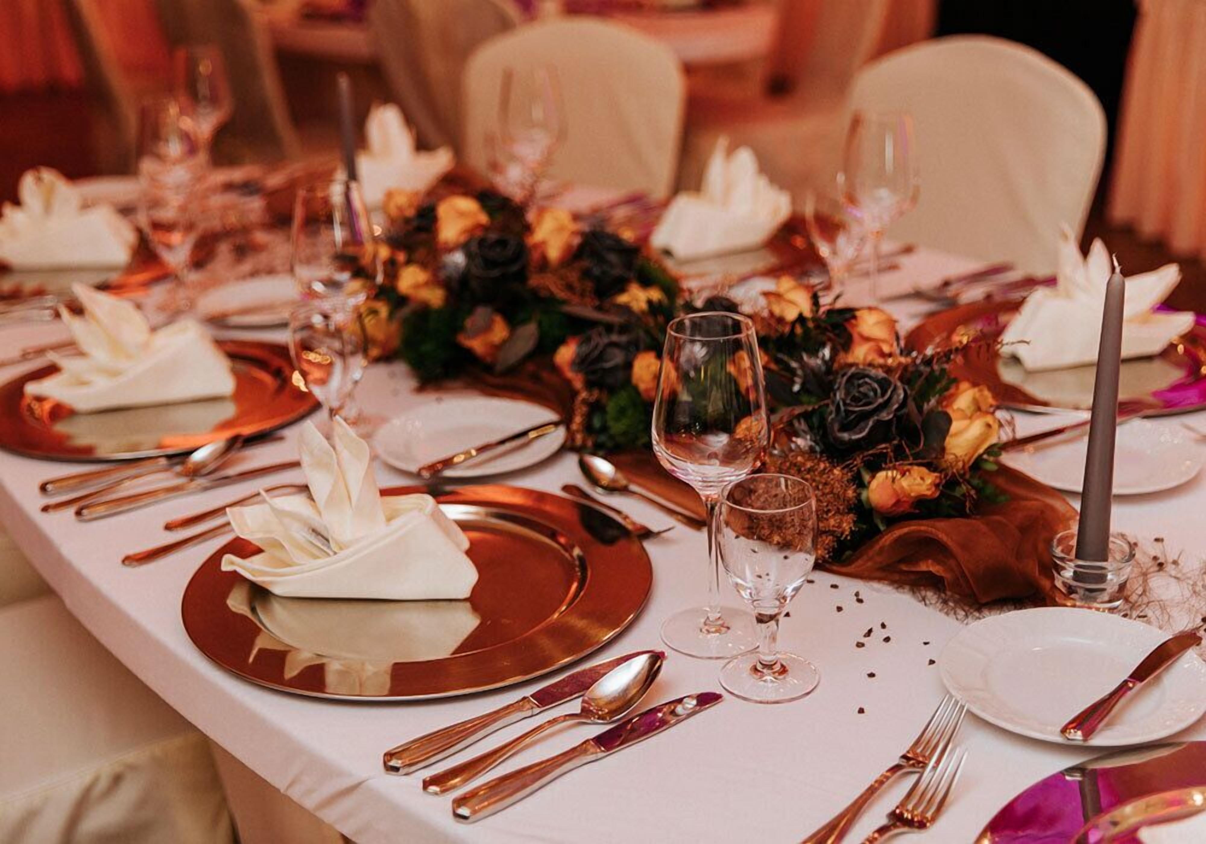 Una mesa dispuesta para una cena formal, con varios cubiertos, platos y copas de vino.