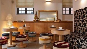 A cozy room with a sofa, a dining table, and several stools. - Al Canal Regio (Venice)