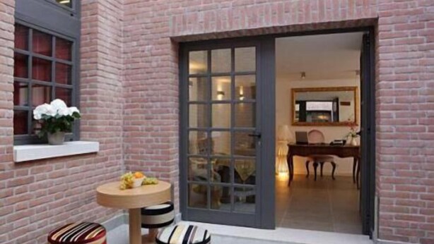 A brick building with a large glass door leading to an interior space. Inside, there is a dining area with a table and chairs. - Al Canal Regio (Venice)