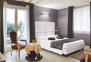 A bedroom with a bed, a chair, a small table, and a window. - Al Canal Regio (Venice)