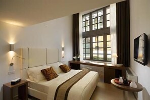 A hotel room with a large bed, bedside tables, a desk, and a window with curtains. - Al Canal Regio (Venice)