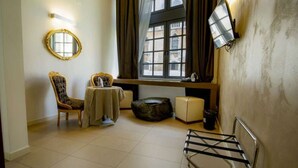 A room with a round mirror, two chairs, a small table, a sofa, and a metal rack. - Al Canal Regio (Venice)