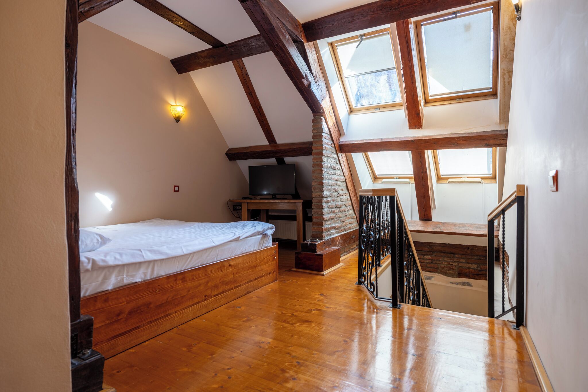 Un dormitorio con una cama de madera, televisión y tragaluz.