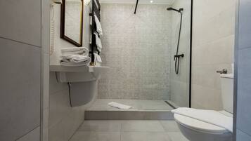 A modern bathroom with a glass shower enclosure, a white sink, and a toilet.