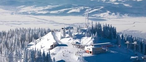 A snow-covered ski resort with cabins, ski lifts, and a mountain backdrop.