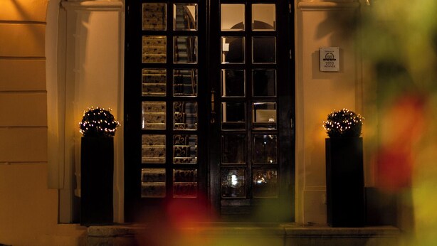 The entrance of Casa Wagner with a dark wooden door, a glass display case, and a decorative light fixture above the door. - Casa Wagner Brasov (Brasov)