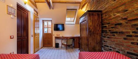 Una habitación con dos camas, un escritorio, una silla, un televisor y una ventana.